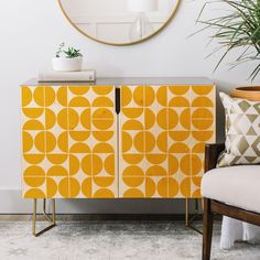 an orange and yellow cabinet next to a white chair with a plant on top of it