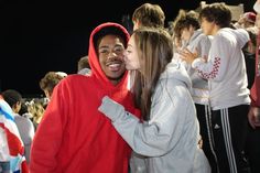 two people are kissing each other in front of a group of young men and women