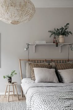 a bed with white sheets and pillows next to a wooden shelf filled with potted plants