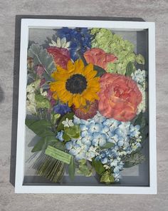 an arrangement of flowers in a white frame