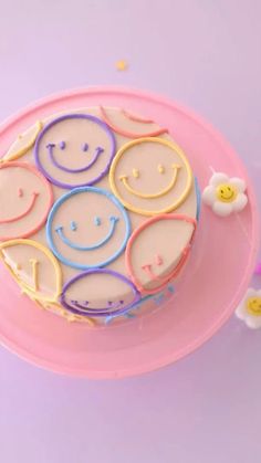 a smiley face cake sitting on top of a pink plate