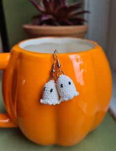 two crocheted sheep are hanging from a mug