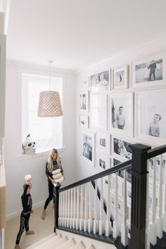 two people are walking up the stairs in a white room with pictures on the wall