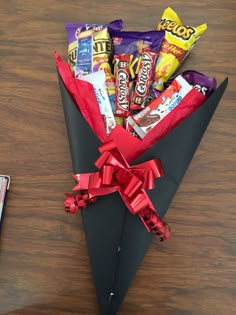 an origami paper bag filled with candy and candies on a wooden table