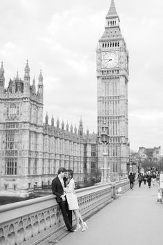 black and white photograph of a couple kissing in front of the big ben clock tower