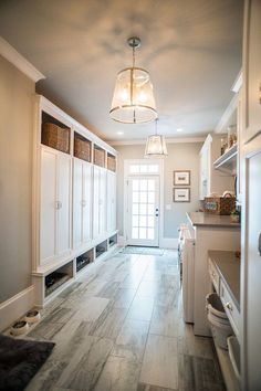 an empty kitchen with white cabinets and wood flooring, along with a light hanging from the ceiling