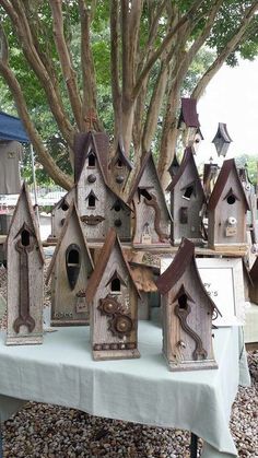 many bird houses are on a table under a tree