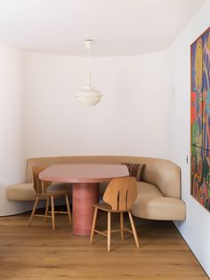 a living room with a couch, table and chairs in front of a painting on the wall