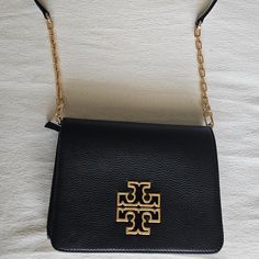 Tory Burch Britten Crossbody Bag Black Leather Great Condition - Has Only Been Used A Couple Of Times Adjustable And Detachable Leather And Gold Chain Strap Can Be Carried As A Clutch One Zippered Compartment One Open Compartment With 2 Bill Slots And Zippered Side Pocket Inside Magnetic Closure Approx. Length 7.75", Height 5.75" Comes From Smoke Free And Pet Free Home Tory Burch Britten Crossbody Bag, Tori Burch Handbags Black, Leather Crossbody Bag Tory Burch, Tory Burch Cross Body Black Bag, Tory Burch Ivory Bags, Tory Burch Crossbody Bag, Black Wallet With Gold-tone Hardware Crossbody, Tory Burch Crossbody, Tory Burch Bag