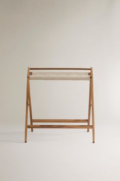 a wooden rack with two cloths on it and one hanging from the top, in front of a white wall