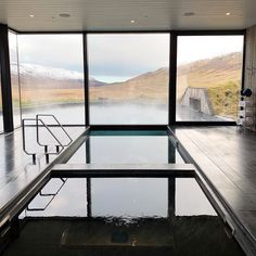 an indoor swimming pool in front of large windows with mountains outside the window and snow on the ground