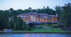 a large house sitting on top of a lush green hillside next to a body of water