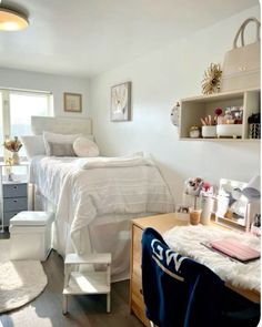 a bedroom with a bed, desk, and other items on the floor in front of a window