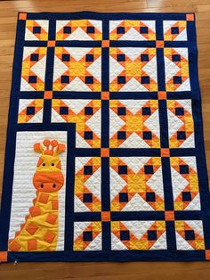 a quilted giraffe is on the floor with an orange and blue border