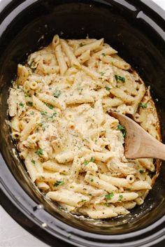 a wooden spoon in a slow cooker filled with pasta