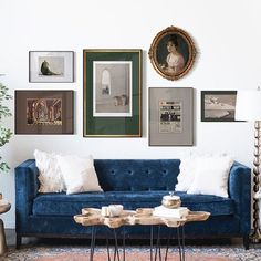 a living room with blue couches and pictures on the wall above them in various frames