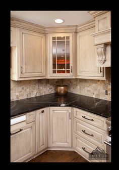 a kitchen with white cabinets and black counter tops