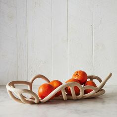 some oranges are sitting in a basket on a marble counter top with white boards behind them