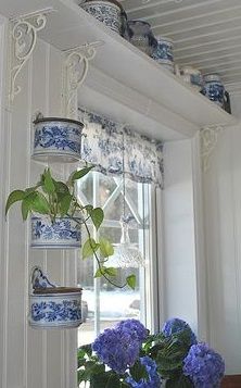 blue and white flowers are in a vase on the window sill