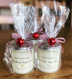 two jars filled with candles sitting on top of a wooden table covered in plastic wrap