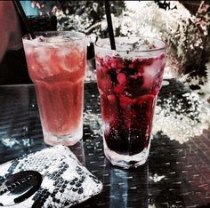 two glasses filled with liquid sitting next to each other on top of a metal table