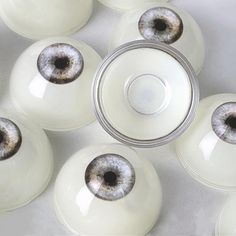 an assortment of white glass bowls with brown and black eyeballs in them on a table