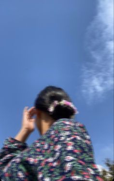 a woman in a kimono looking up into the sky with her hand on her head