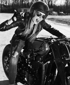 a woman sitting on top of a motorcycle in the dirt with her hand on the wheel