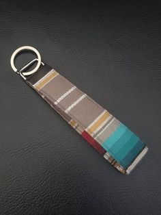 a keychain that is sitting on top of a black surface with a blue and brown stripe