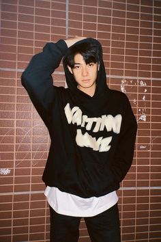 a young man wearing a black hoodie with white writing on it