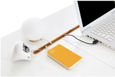 a laptop computer sitting on top of a white desk next to a yellow and white charger