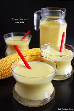 two glasses filled with corn on the cob next to a jar of milk and a red straw