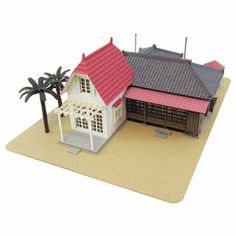 a paper model of a house with a red roof and palm trees in front of it