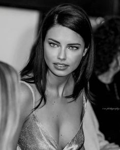 black and white photograph of a woman with very large breast wearing a shiny dress looking at the camera