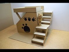 an orange cat standing on top of a cardboard box with stairs and paw prints painted on it