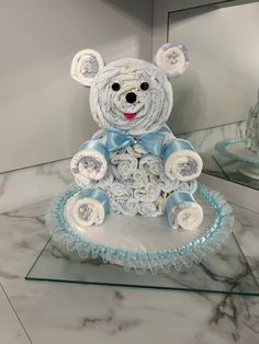 a teddy bear made out of flowers sitting on top of a glass table next to a mirror