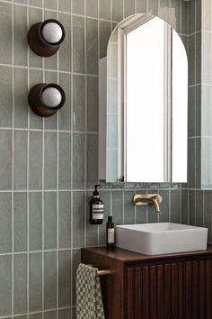 a bathroom with a sink, mirror and soap dispenser