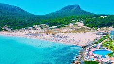 an aerial view of the beach and surrounding resort area with mountains in the back ground