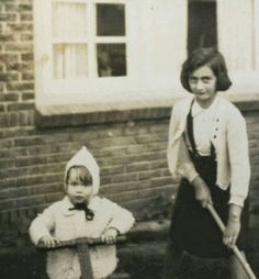 an old black and white photo of two children with baseball bats in front of a brick building