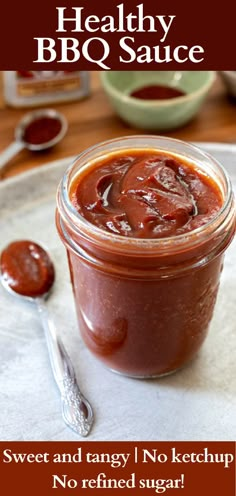 a jar of bbq sauce sitting on top of a table next to a spoon