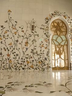 an intricately designed wall with flowers and vines in the middle is painted on white tiles