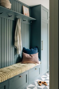 a bench that has some pillows on top of it and a coat rack in the background