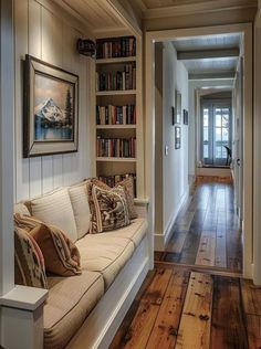 the hallway is lined with bookshelves and couches, along with pictures on the wall