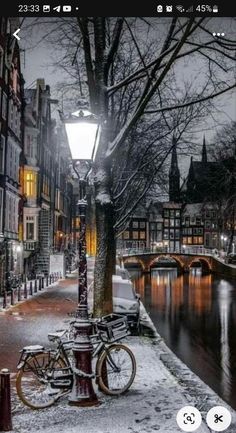 a bike parked next to a lamp post on a snowy street with buildings in the background