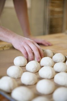 a person is kneading dough balls on a baking sheet to bake them