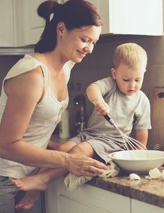 a woman and child are in the kitchen preparing food together with whisk attachments