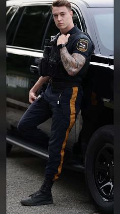 a man with tattoos standing next to a police car