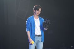 a young man holding a baseball glove and ball in his right hand while standing on stage