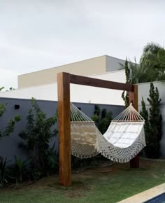 a white hammock sitting on top of a lush green field next to a swimming pool