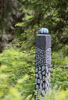 a sculpture is in the middle of some tall grass and trees with green leaves around it